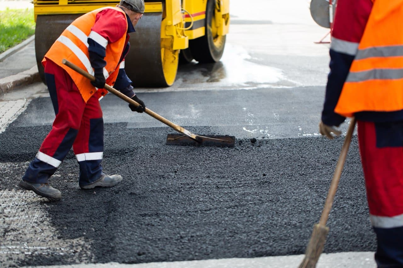 Workers patching a damaged section of asphalt road